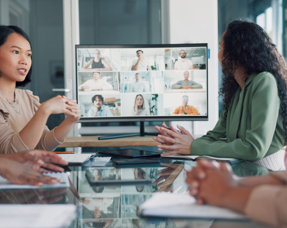 Medewerkers in een moderne hybride vergaderruimte die met één druk op de knop een meeting starten via Unite.
